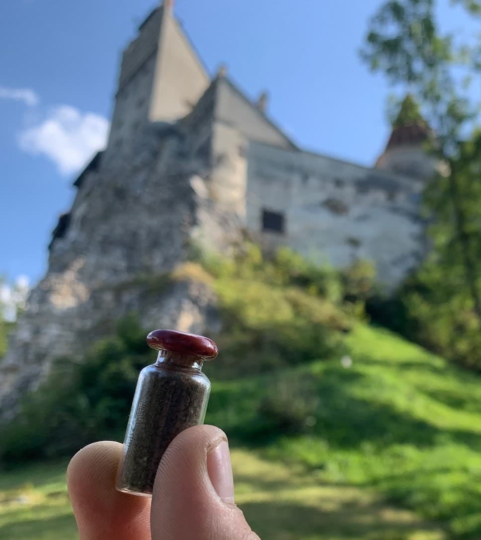 Holding a Dracula's Soil bottle in front of Bran Castle